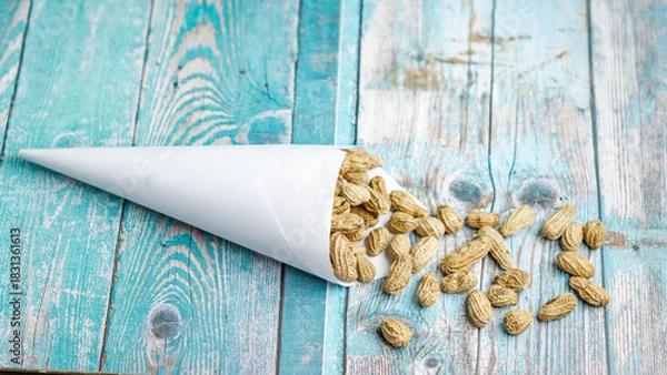 Fototapeta Boiled peanuts wrapped in cone-shaped paper on a rustic table