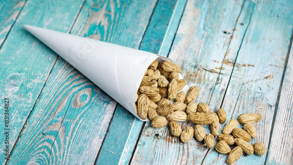 Fototapeta Boiled peanuts wrapped in cone-shaped paper on a rustic table