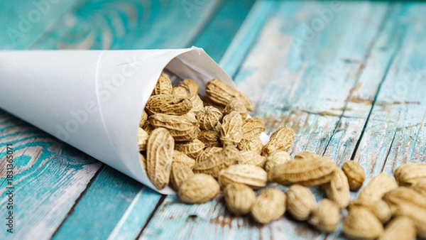 Fototapeta Boiled peanuts wrapped in cone-shaped paper on a rustic table