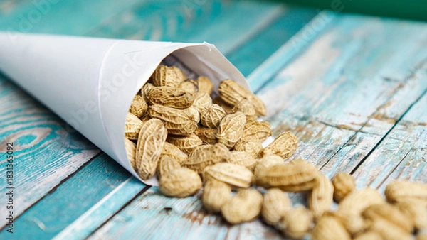 Fototapeta Boiled peanuts wrapped in cone-shaped paper on a rustic table