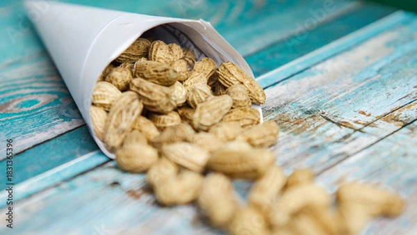 Fototapeta Boiled peanuts wrapped in cone-shaped paper on a rustic table