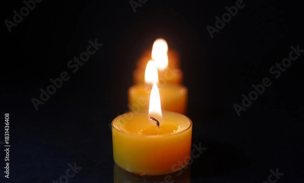 Fototapeta Tealight Candle Burning in Front with Soft Bokeh Flames Behind  Single Candle Flame in Focus with Blurred Candles in Background