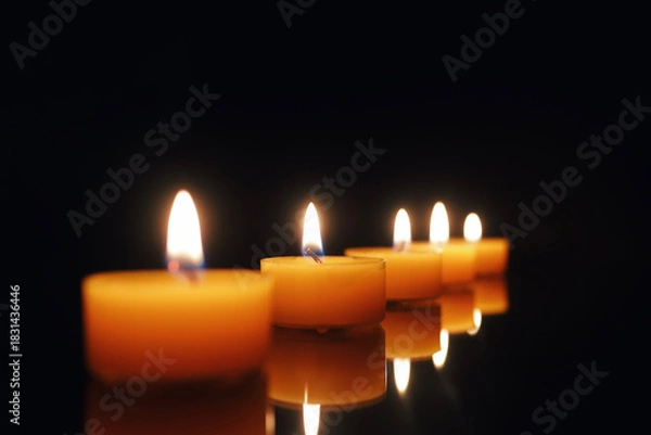 Fototapeta Row of Burning Tealight Candles on Dark Background Multiple Glowing Candle Flames Aligned in Soft Darkness