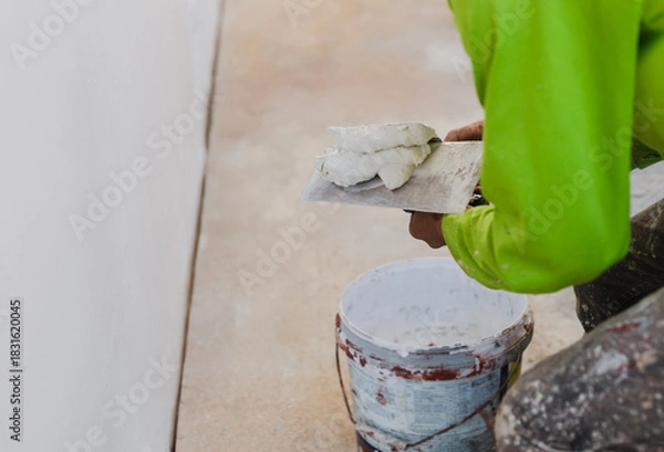Obraz Worker with wall plastering tools renovating house.