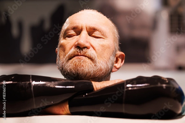 Fototapeta Portrait of grey haired free diver in wetsuit resting at poolside 