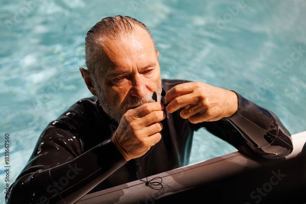 Fototapeta Grey haired diver holding nose clip at poolside 