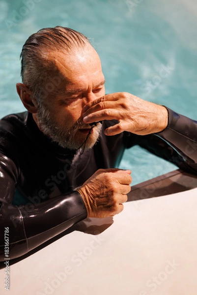Fototapeta Grey haired diver wearing nose clip at poolside 