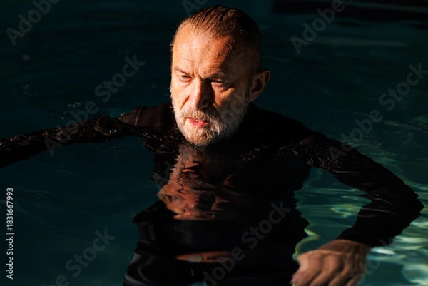Fototapeta Senior diver in wetsuit standing in swimming pool with light