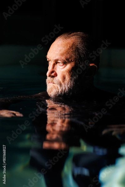 Fototapeta Portrait of grey haired diver swimming in pool with lighting 