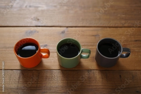 Obraz Three colorful coffee mugs filled with dark coffee on a wooden table