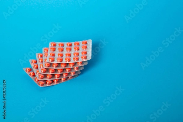 Obraz A stack of pills on a blue background for toothache and herpes. Copy space for text, metabolism