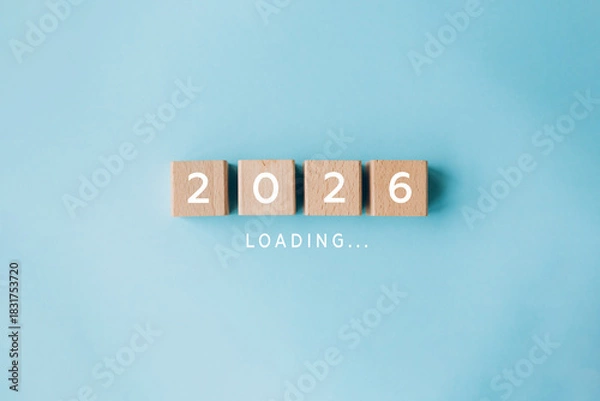 Fototapeta 2026 loading concept with wooden cubes on blue background. Concept of new year arrival, anticipation, future plans, and transition from 2025 to 2026.