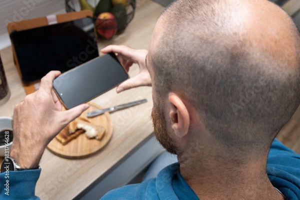 Obraz Man taking a photo of breakfast with his phone
