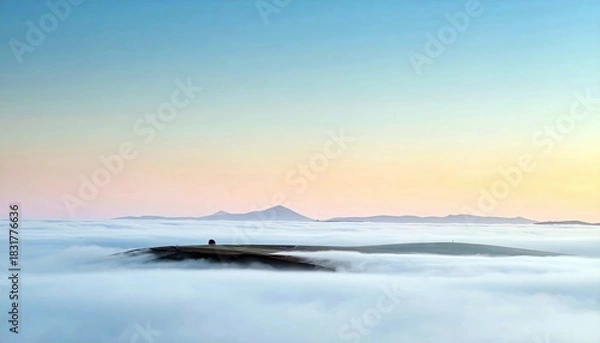 Obraz A landscape image of a hill emerging from a sea of clouds at sunrise, with a colorful sky.