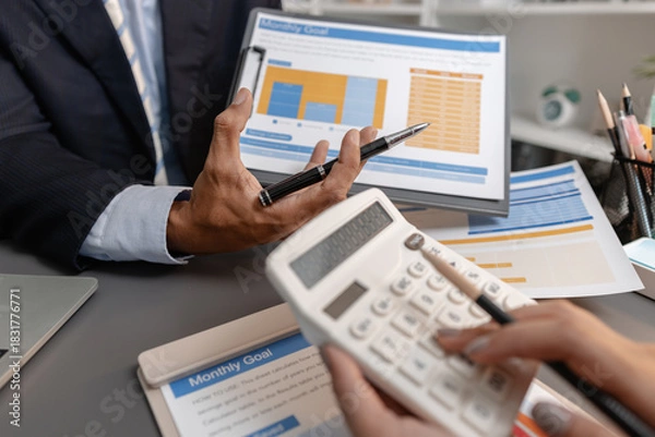 Fototapeta Business professionals reviewing financial charts and performance reports during a meeting, highlighting strategic planning, budget analysis, and teamwork in a modern corporate environment.