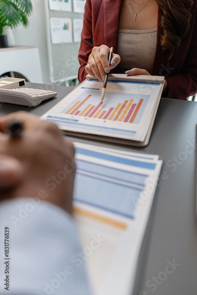 Fototapeta Business professionals reviewing financial charts and performance reports during a meeting, highlighting strategic planning, budget analysis, and teamwork in a modern corporate environment.