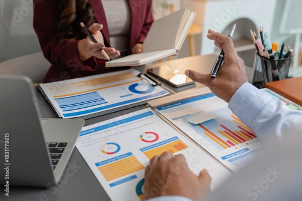 Fototapeta Business colleagues reviewing budget charts together in a modern office, focusing on financial insights, performance metrics, and strategic planning to support upcoming business decisions.