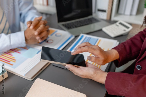 Obraz Business colleagues reviewing budget charts together in a modern office, focusing on financial insights, performance metrics, and strategic planning to support upcoming business decisions.