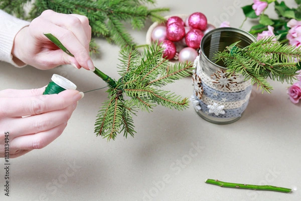 Obraz Florist at work: woman shows how to make modern Christmas decoration with fir, roses, pink baubles and decorative stars. The base is classic can. Step by step, complete tutorial.