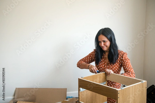 Fototapeta A woman is working on assembling a piece of furniture