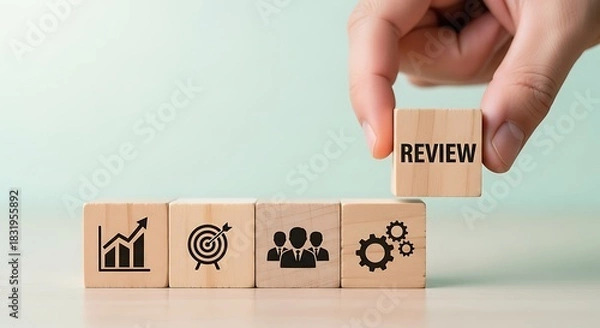 Fototapeta Business performance review concept hand placing a block with the word review on top of blocks with business icons