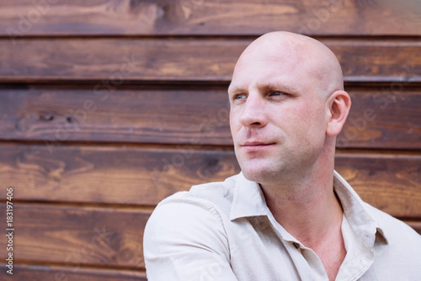Obraz portrait of handsome bald man, on the wooden brawn backrgound. beige natural shirt. pring. summer. how weather, barbershop