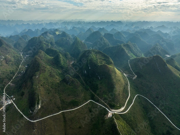 Fototapeta Winding Mountain Road Snaking Through Dramatic Karst Peaks in Aerial View of Guangxi China