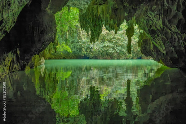 Fototapeta Perfect Mirror Reflection of Cave Entrance and Lush Vegetation on Calm Underground River in Guangxi China