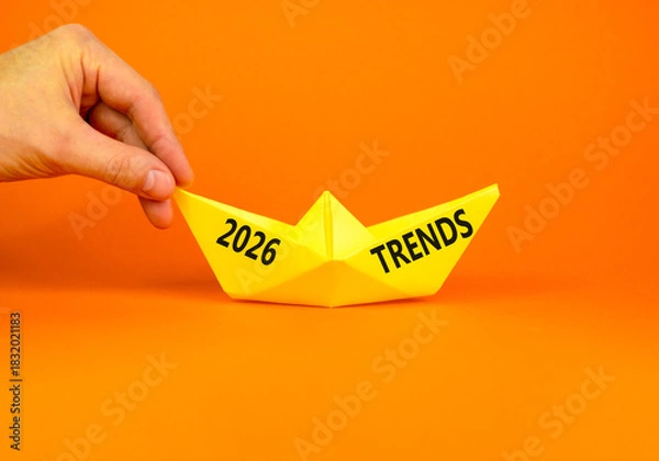 Fototapeta 2026 Trends new year symbol. Concept words 2026 Trends on beautiful yellow paper boat. Beautiful orange paper background. Businessman's hand. Business and 2026 Trends new year concept. Copy space.