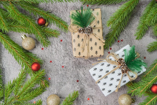 Obraz Christmas composition. Gift boxes, fir tree branches, red and gold decorations on grey background. High quality photo