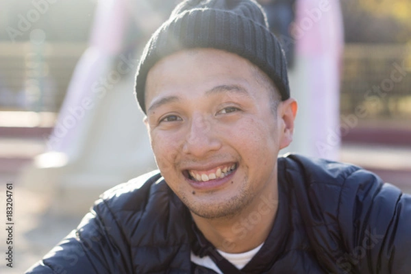 Obraz ット帽の日本人男性が屋外で笑顔になるポートレート｜親しみやすいプロフィール・ビジネス素材