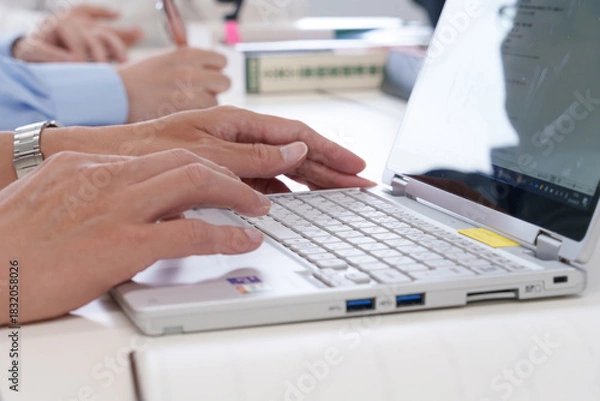 Obraz 会議室でノートパソコンを操作する若い男性の手元