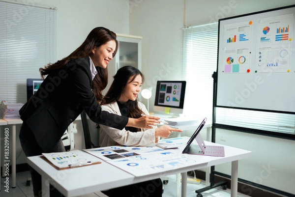 Obraz Businesswomen collaborating on data analysis using tablet in office