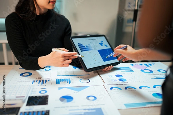 Obraz Business people analyzing financial data using tablet and papers