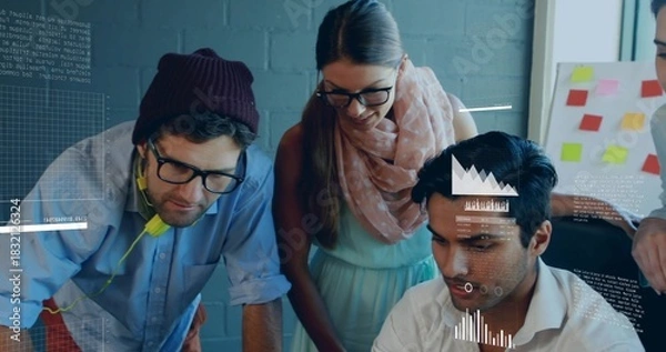 Obraz Collaborating team wearing beanie and scarf reviewing laptop in modern office, with sticky notes