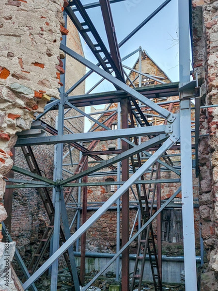 Fototapeta Historic brick building ruins with metal support frames in Old Riga, Latvia, under restoration