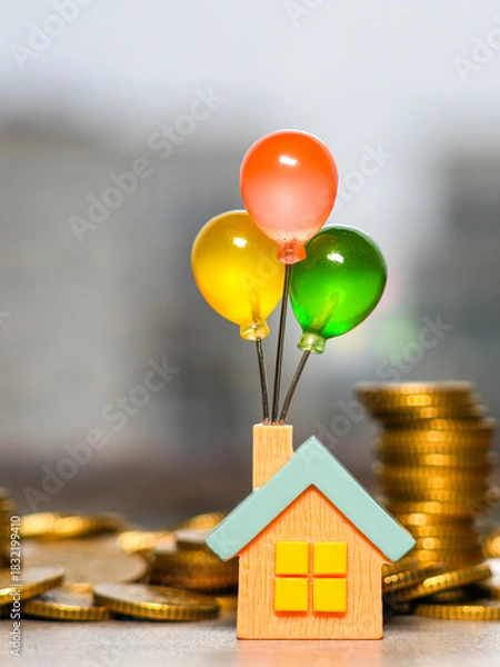 Fototapeta Colorful balloon house figurine surrounded by gold coins symbolizing dreams of owning a home