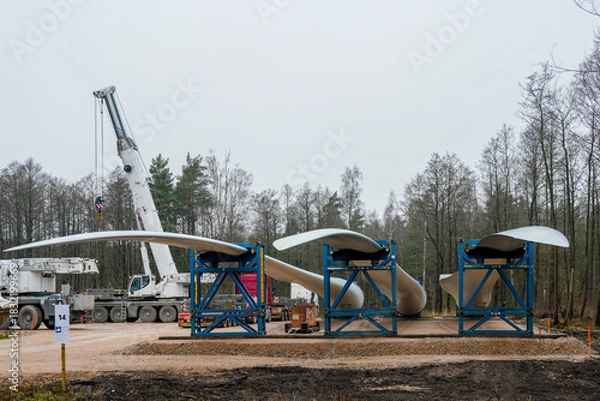 Fototapeta Wind turbine blades prepared for installation with crane and support frames at a renewable energy site