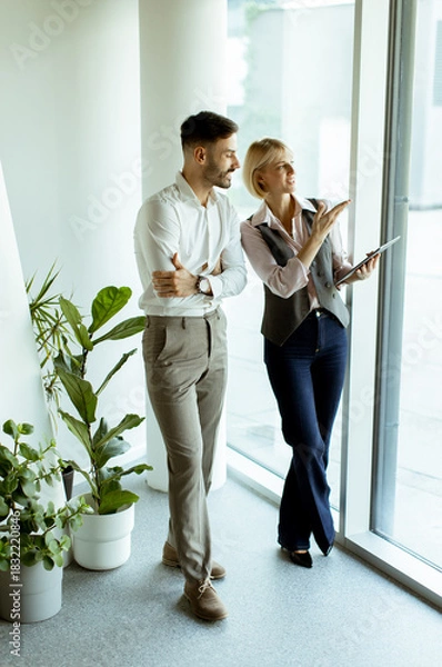 Fototapeta Discussing ideas by the window in a modern office setting during daylight hours