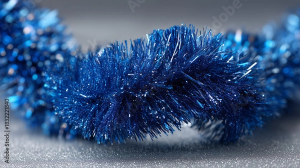 Fototapeta A close up of a shiny blue christmas tinsel garland on a glittery surface