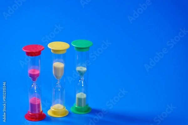 Obraz Hourglasses on blue background with copy space