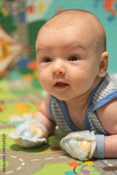 Fototapeta Newborn Baby lying on stomach in scratch mittens. Protect hands from accidental scratches. Babycare and safety