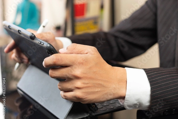 Fototapeta a male hands of a business man on suit using a digital tablet and working at home