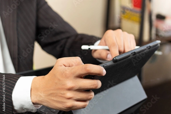 Fototapeta a business man on suit at the left side of the screen using a tablet