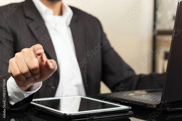 Fototapeta a business man on suit pointing with his right index finger to something on the front of him