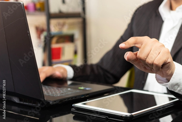 Fototapeta a business man on suit at the right side of the screen pointing with his left index finger to something on the front of him