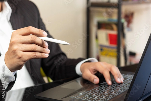 Fototapeta a right hand of a business man on suit pointing to the screen of a laptop