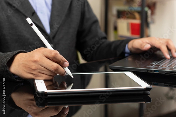 Fototapeta a right hand of a modern business man ready to design something on a white tablet at the left side of the screen