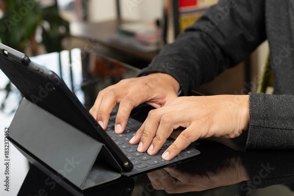 Fototapeta a male hands typing on a grey tablet keyboard