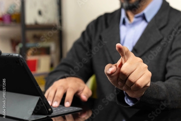 Fototapeta a modern business man working from home pointing with his left index finger to something in the space